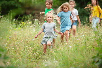 Image showing Kids, children running on green meadow, forest. Childhood and summertime