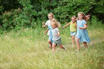 Image showing Kids, children running on green meadow, forest. Childhood and summertime