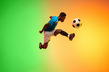 Image showing Male soccer, football player training in action isolated on gradient studio background in neon light