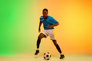 Image showing Male soccer, football player training in action isolated on gradient studio background in neon light