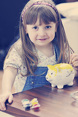 Image showing cute little girl painting piggy bank