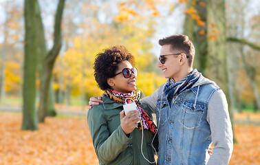 Image showing couple with smartphone and earphones in autumn