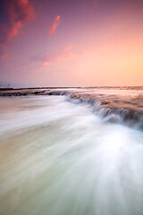 Image showing Cascading waves flowing over the exposed rock shelf early mornin