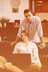 Image showing joyful couple relax and work on laptop computer at modern home