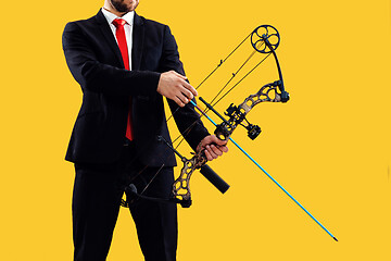 Image showing Businessman aiming at target with bow and arrow, isolated on yellow background