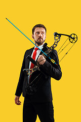 Image showing Businessman aiming at target with bow and arrow, isolated on yellow background