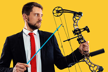 Image showing Businessman aiming at target with bow and arrow, isolated on yellow background