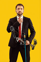 Image showing Businessman aiming at target with bow and arrow, isolated on yellow background