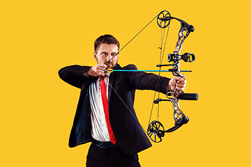 Image showing Businessman aiming at target with bow and arrow, isolated on yellow background