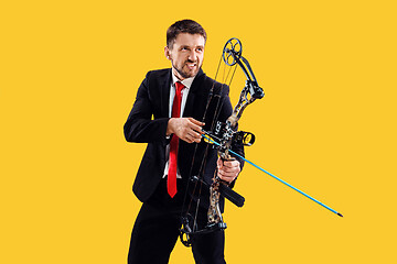 Image showing Businessman aiming at target with bow and arrow, isolated on yellow background