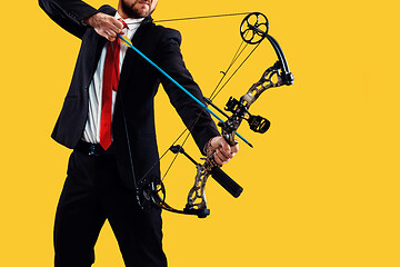 Image showing Businessman aiming at target with bow and arrow, isolated on yellow background