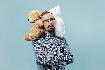 Image showing Tired man sleeping at home having too much work. Bored businessman with pillow and toy bear
