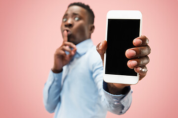 Image showing Indoor portrait of attractive young black man holding blank smartphone