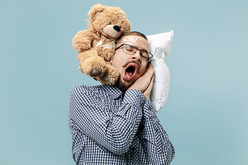 Image showing Tired man sleeping at home having too much work. Bored businessman with pillow and toy bear