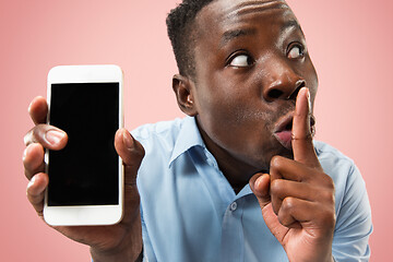 Image showing Indoor portrait of attractive young black man holding blank smartphone