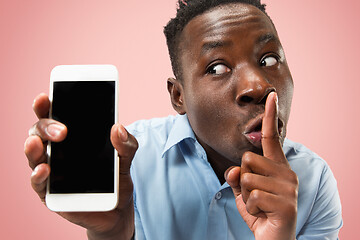 Image showing Indoor portrait of attractive young black man holding blank smartphone