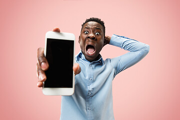 Image showing Indoor portrait of attractive young black man holding blank smartphone