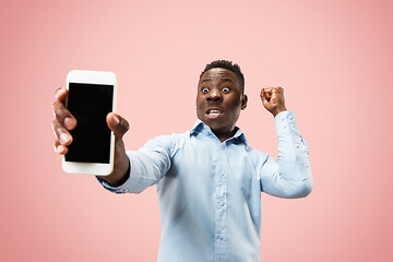 Image showing Indoor portrait of attractive young black man holding blank smartphone