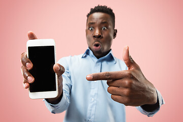 Image showing Indoor portrait of attractive young black man holding blank smartphone