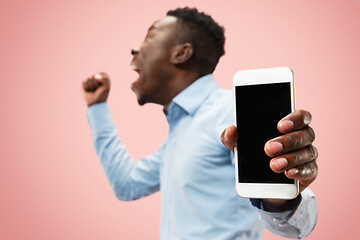 Image showing Indoor portrait of attractive young black man holding blank smartphone