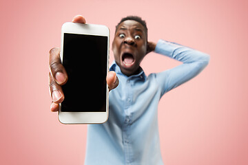 Image showing Indoor portrait of attractive young black man holding blank smartphone