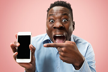 Image showing Indoor portrait of attractive young black man holding blank smartphone