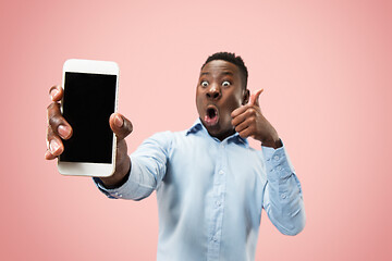 Image showing Indoor portrait of attractive young black man holding blank smartphone