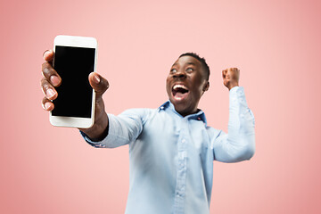 Image showing Indoor portrait of attractive young black man holding blank smartphone