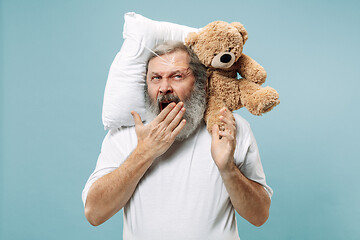 Image showing Tired man sleeping at home having too much work. Bored businessman with pillow and toy bear