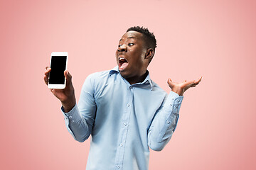 Image showing Indoor portrait of attractive young black man holding blank smartphone