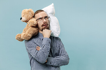 Image showing Tired man sleeping at home having too much work. Bored businessman with pillow and toy bear