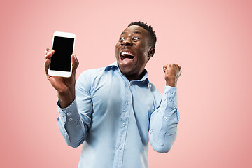 Image showing Indoor portrait of attractive young black man holding blank smartphone