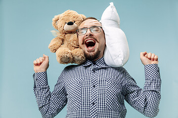 Image showing Tired man sleeping at home having too much work. Bored businessman with pillow and toy bear