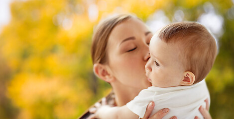 Image showing happy young mother kissing little baby in autumn
