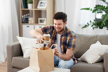 Image showing smiling man unpacking takeaway food at home