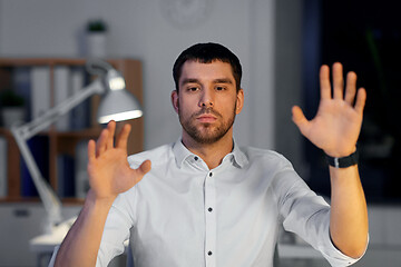 Image showing businessman using gestures at night office