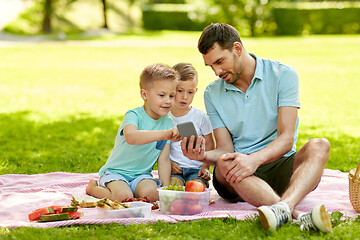 Image showing family with smartphone having picnic at park