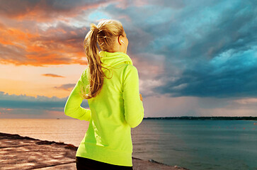 Image showing woman with earphones running over sea sunset