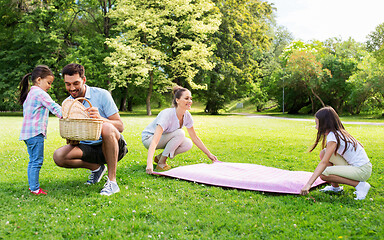 Image showing family laying down picnic blanket in summer park