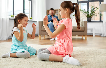 Image showing happy little sisters playing clapping game at home