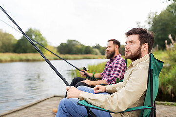 Image showing male friends with fishing rods on lake