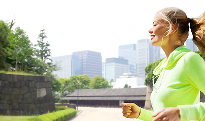 Image showing woman with earphones running at city park