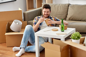 Image showing smiling man eating takeaway food at new home