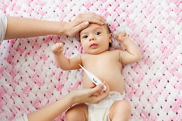 Image showing mother\'s hands measuring temperature of baby girl