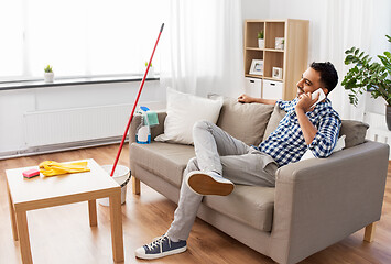 Image showing man calling on smartphone after cleaning home