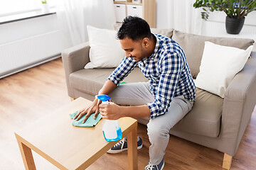 Image showing indian man cleaning table with detergent at home