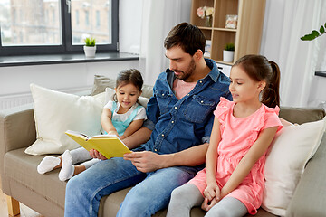 Image showing happy father with daughters reading book at home