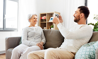 Image showing adult son photographing senior mother at home