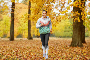 Image showing young woman running in autumn park