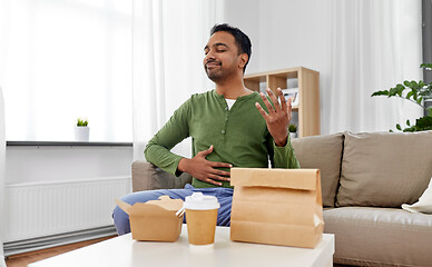 Image showing pleased indian man eating takeaway food at home